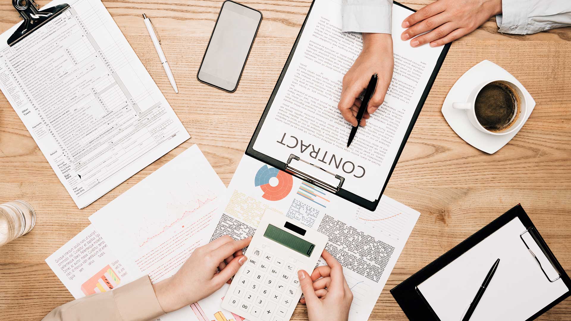 hands of accounting team members holding a calculator and a pen over papers